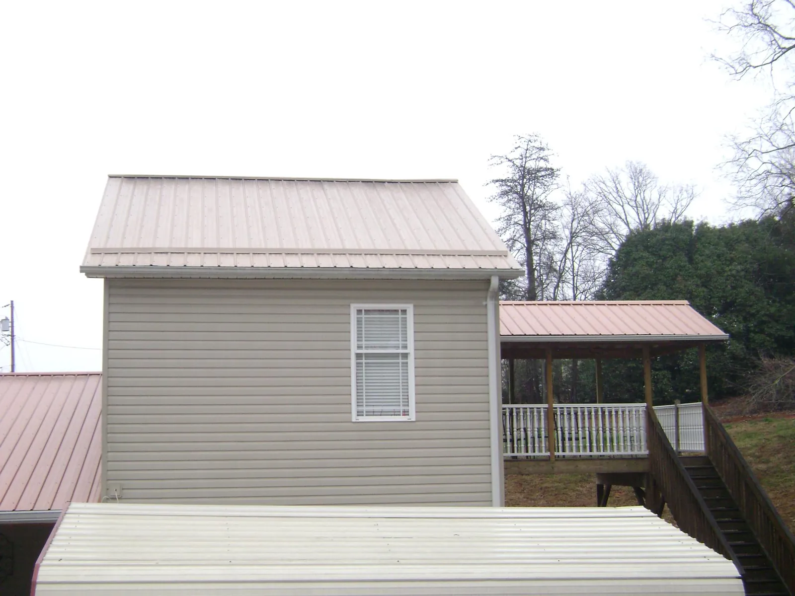 Tan metal roofs on a two story addition and attached porch, from a Roof Replacement job in Malden
