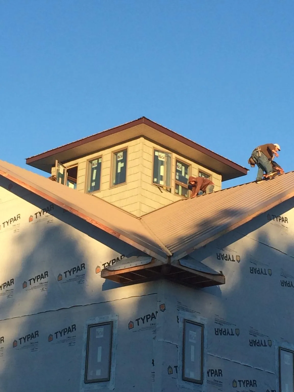 Roofers working around a rooftop cupola on a new metal roof at sunset — Roof Waterproofing in Malden by Roofing Brothers